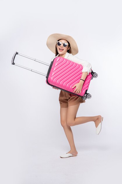 Mujer con sombrero, gafas y asas de maletas para viajar