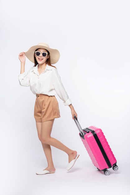 Mujer con sombrero, gafas y asas de maletas para viajar