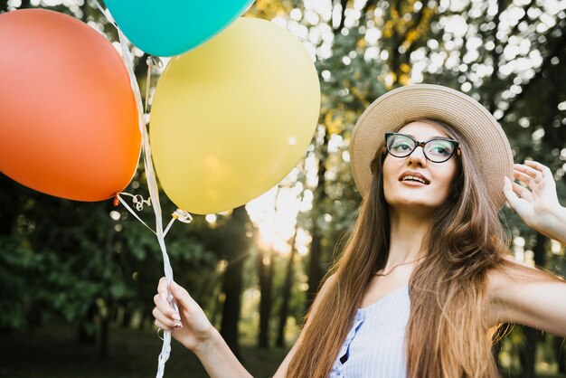 Mujer con sombrero y globos en el parque