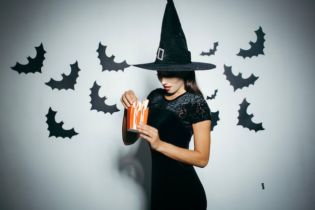 Mujer en sombrero de Halloween con caja de comida