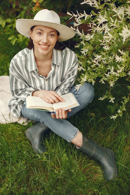 Mujer con sombrero con un libro en un jardín