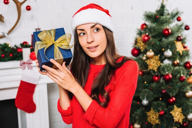 Mujer en sombrero de Navidad con caja actual
