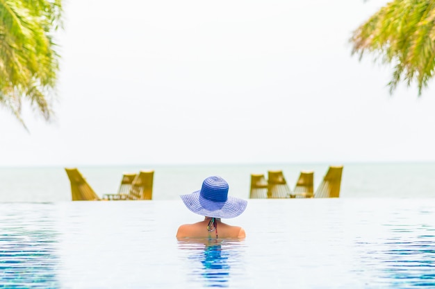 Mujer con sombrero en la piscina del hotel resort