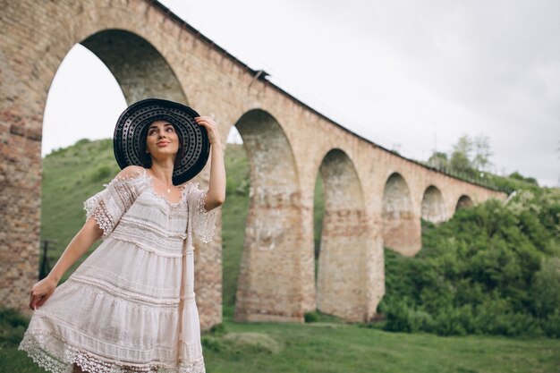 Mujer con sombrero por el puente del ferrocarril