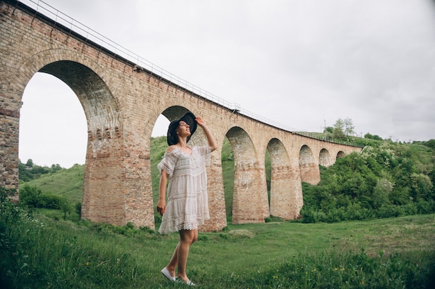 Foto gratuita mujer con sombrero por el puente del ferrocarril