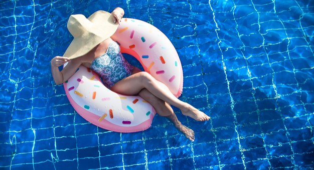 Una mujer con sombrero se relaja en un círculo inflable en la piscina.