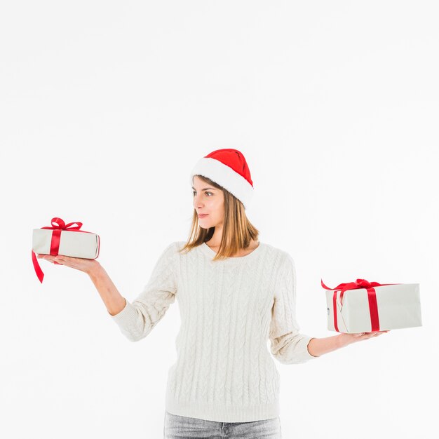 Mujer en sombrero rojo de santa con cajas de regalo