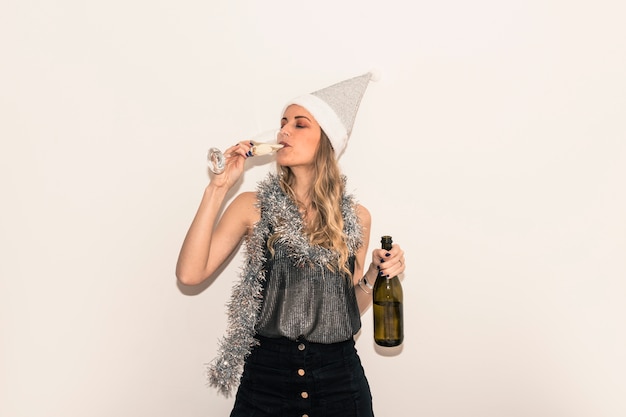 Mujer con sombrero de Santa bebiendo champán de vidrio