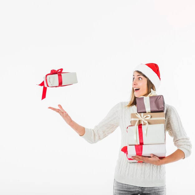 Mujer en sombrero de santa lanzando caja de regalo