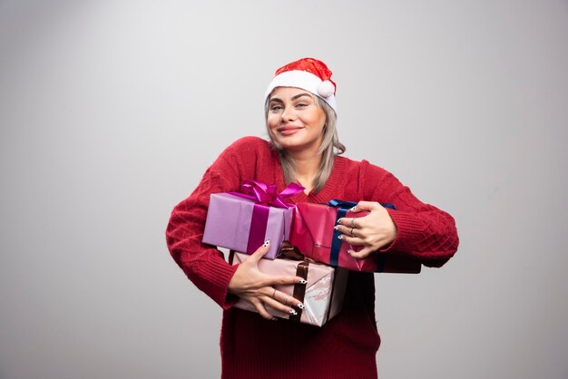 Mujer con sombrero de Santa con montón de cajas de regalo.