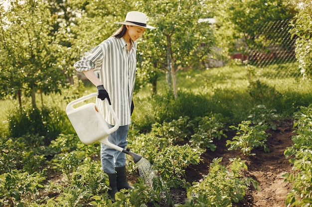 Foto gratuita mujer con sombrero sosteniendo embudo y trabaja en un jardín.