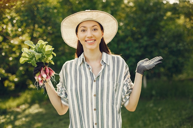 Foto gratuita mujer con sombrero sosteniendo rábanos frescos