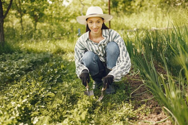 Mujer con sombrero trabajando en un jardín.