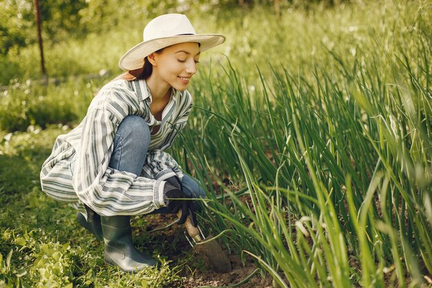 Mujer con sombrero trabajando en un jardín.