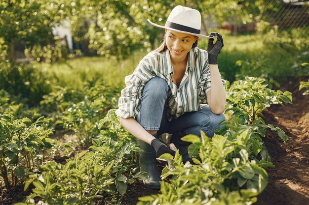 Mujer con sombrero trabajando en un jardín.