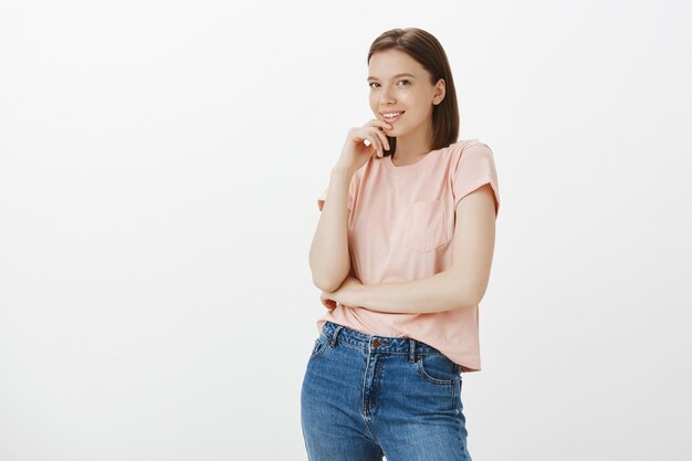 Mujer soñadora coqueta mirando algo tentador, mordiendo el dedo y sonriendo tontamente