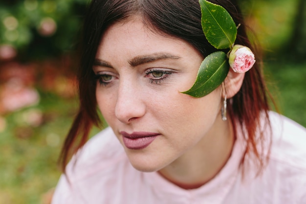 Mujer soñadora con flores en cabello castaño