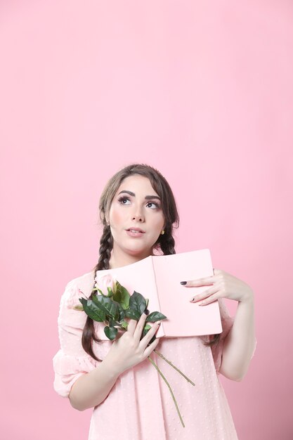 Mujer soñadora posando con rosas y libro