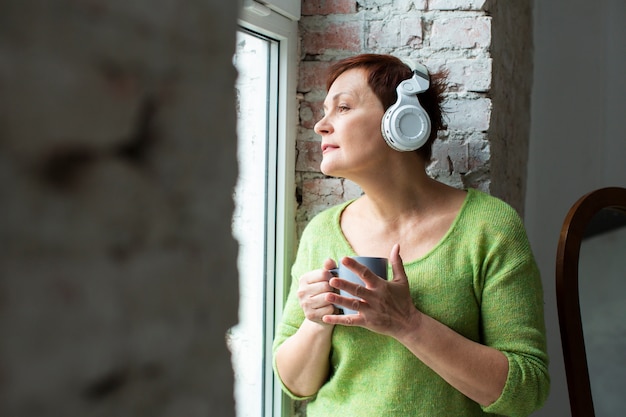 Foto gratuita mujer soñadora senior escuchando música