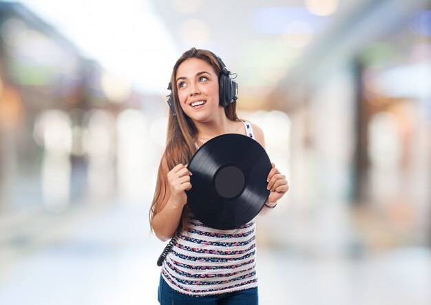 Mujer sonriendo con auriculares y un disco de vinilo