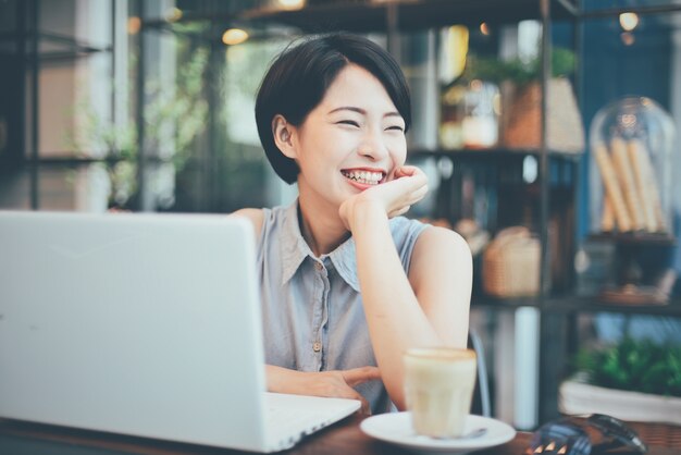 Mujer sonriendo con un café y un portátil