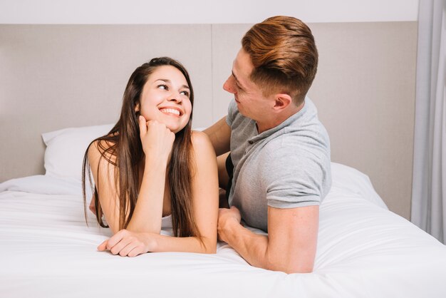 Mujer sonriendo en la cama mientras mira a su novio