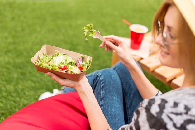 Mujer sonriendo y comiendo en el parque