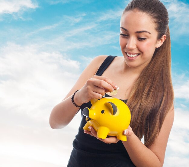 Mujer sonriendo echando una moneda a una hucha