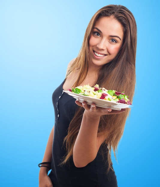 Mujer sonriendo con una ensalada en las manos