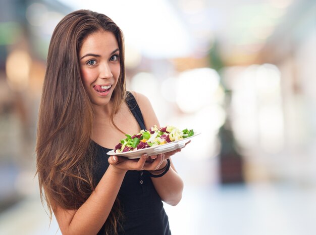 Mujer sonriendo con una ensalada en las manos