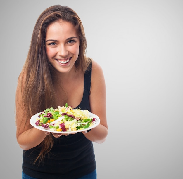 Mujer sonriendo con una ensalada en las manos