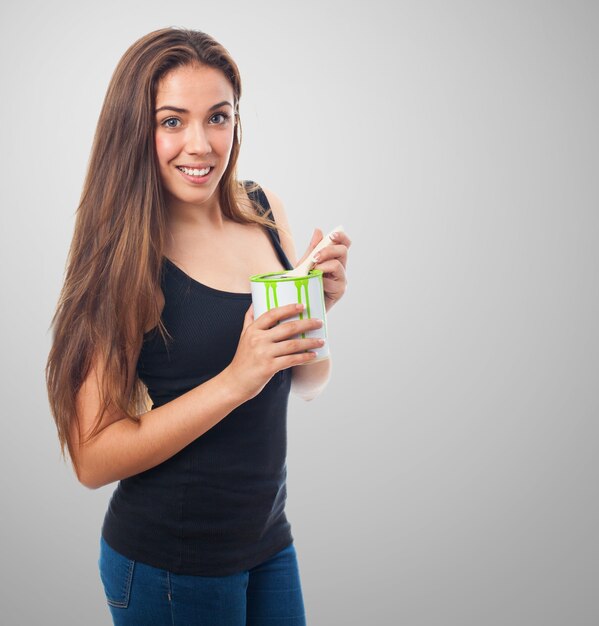 Mujer sonriendo con una lata de pintura verde