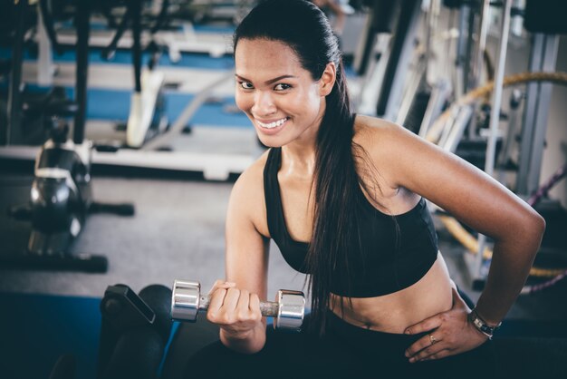 Mujer sonriendo levantando pesas