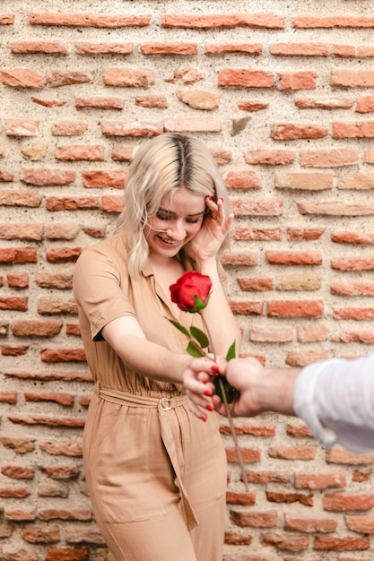 Mujer sonriendo mientras le dan una rosa