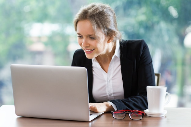 Mujer sonriendo mientras escribe en un portátil