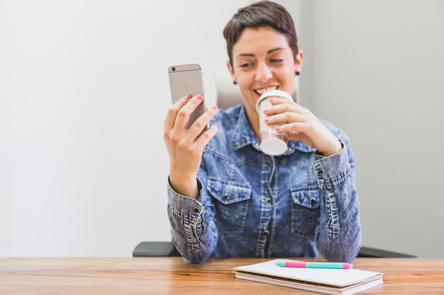 Foto gratuita mujer sonriendo y mirando su móvil