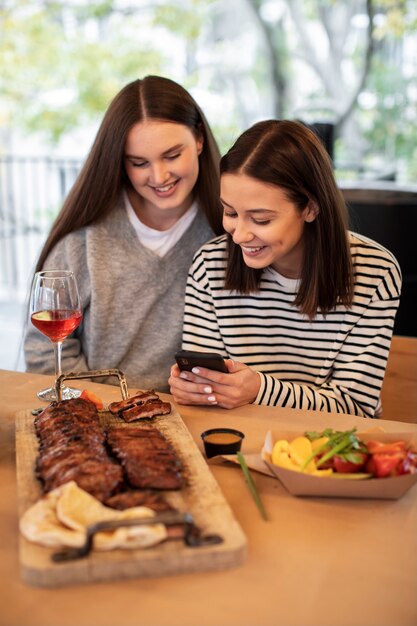 Mujer sonriendo y mostrando su teléfono a su amiga