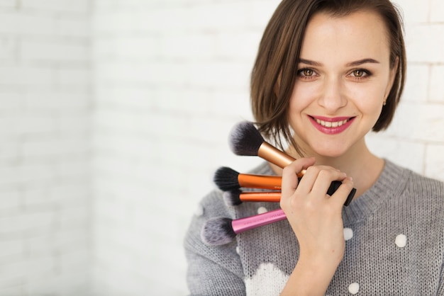 Mujer sonriendo con pinceles makeup