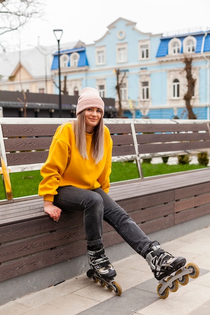 Foto gratuita mujer sonriendo y posando en un banco con patines