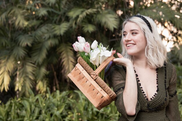 Mujer sonriendo y posando con canasta de flores