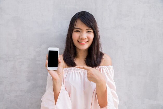 Mujer sonriendo señalando su móvil