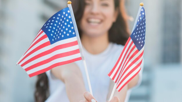 Mujer sonriendo y sosteniendo banderas de Estados Unidos