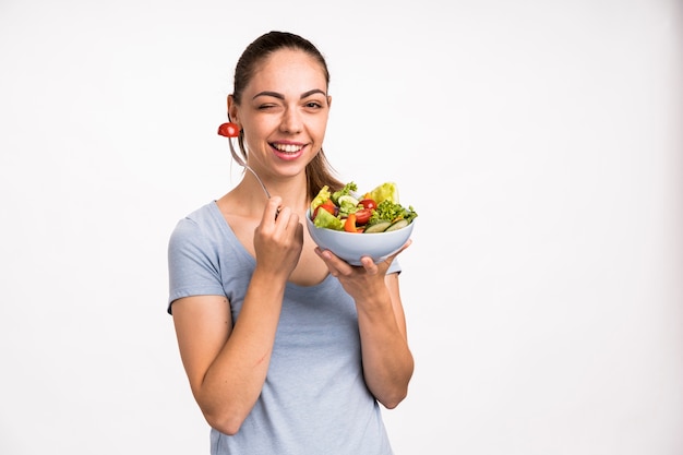 Mujer sonriendo y sosteniendo una ensalada