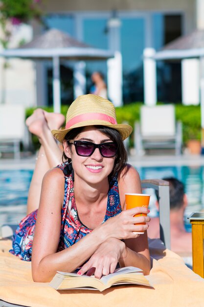 Mujer sonriendo con un vaso y un libro