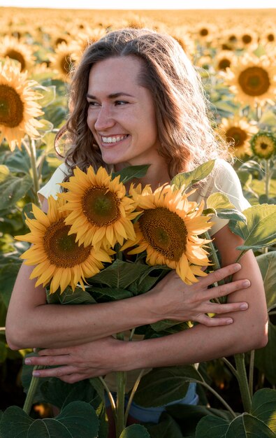 Mujer sonriente abrazando girasoles