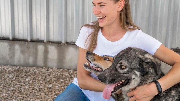 Mujer sonriente abrazando perros de rescate lindos
