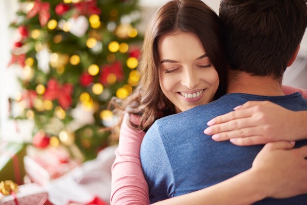 Mujer sonriente abrazando a su novio en Navidad