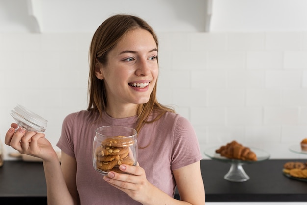 Mujer sonriente abriendo un frasco con galletas