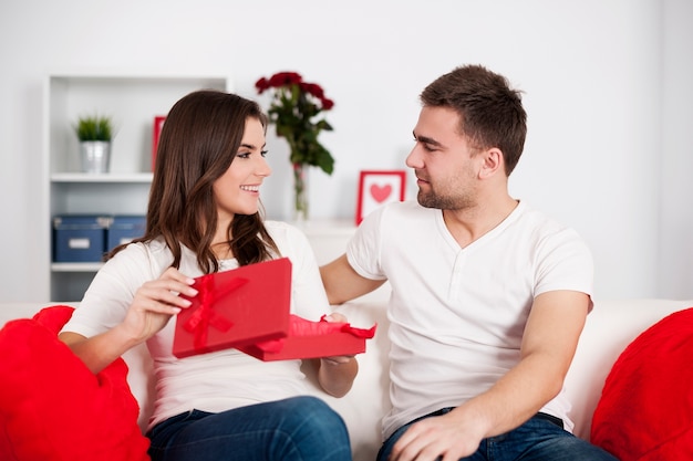 Mujer sonriente abriendo un regalo de San Valentín