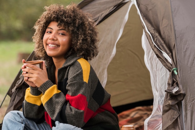 Mujer sonriente acampando al aire libre con carpa